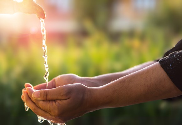 Farmer collecting water in their hand from a tap