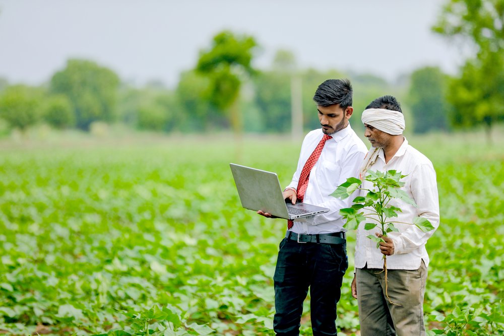 Software techie showing something on the laptop to a farmer
