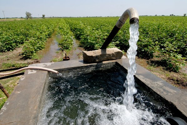 Water from a pump filling up an open tank in a farm