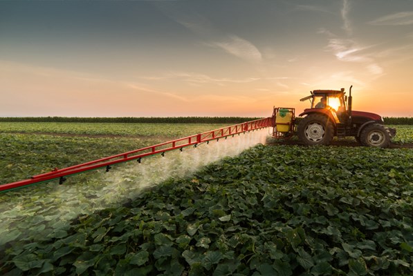 Tractor spraying pesticide on crops