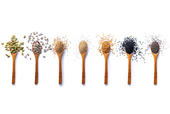 Several spoons filled with different types of seeds and grains
