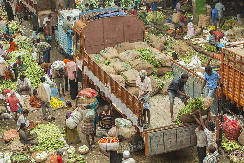 A truck loaded with sacks of greens in an open market