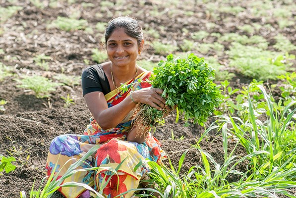 Woman holding a bunch of fresh greens in a field