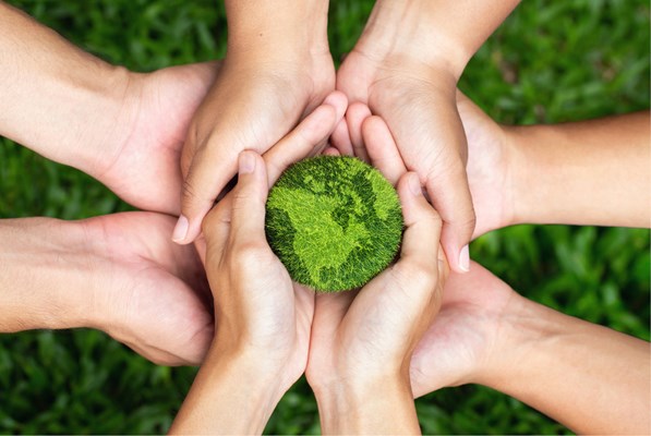 Several palms cradling a green Earth model