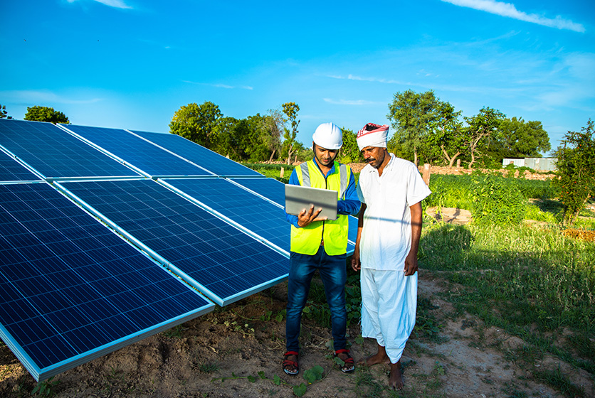 Technician interacting with a farmer on a field with solar panels