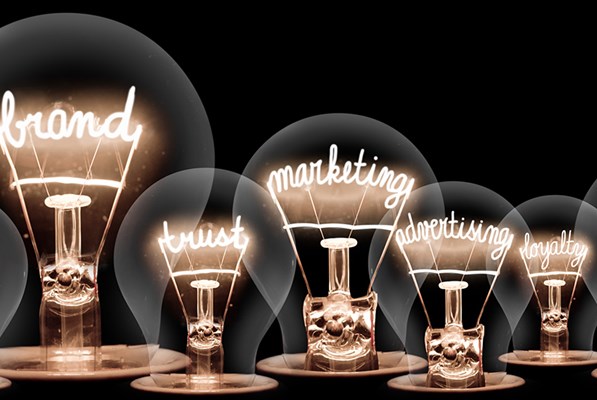 Several bulbs lit with words design, branding, logo, marketing, trust, advertising, quality and loyalty