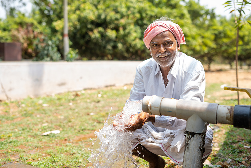 Farmer washing hands in water from a pump