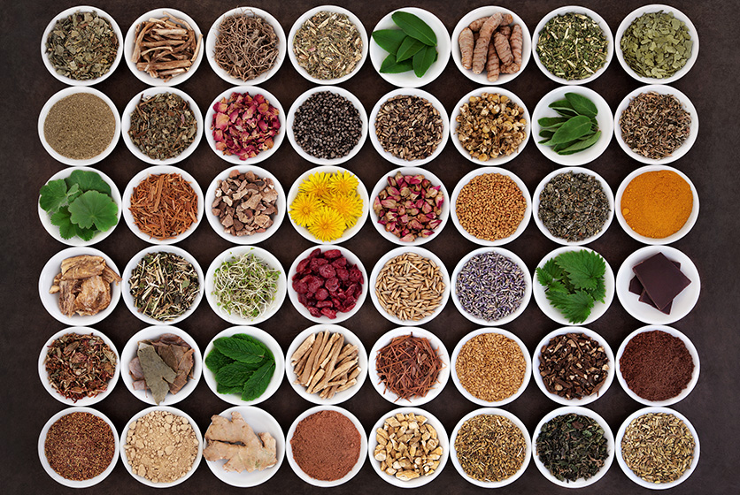 Different types of herbs in bowls arranged as a square