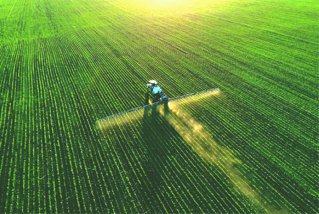 Tractor spraying fertilizer on a green field