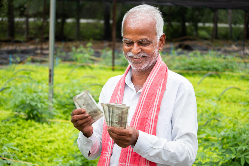 Happy Indian farmer counting currency notes in a green field