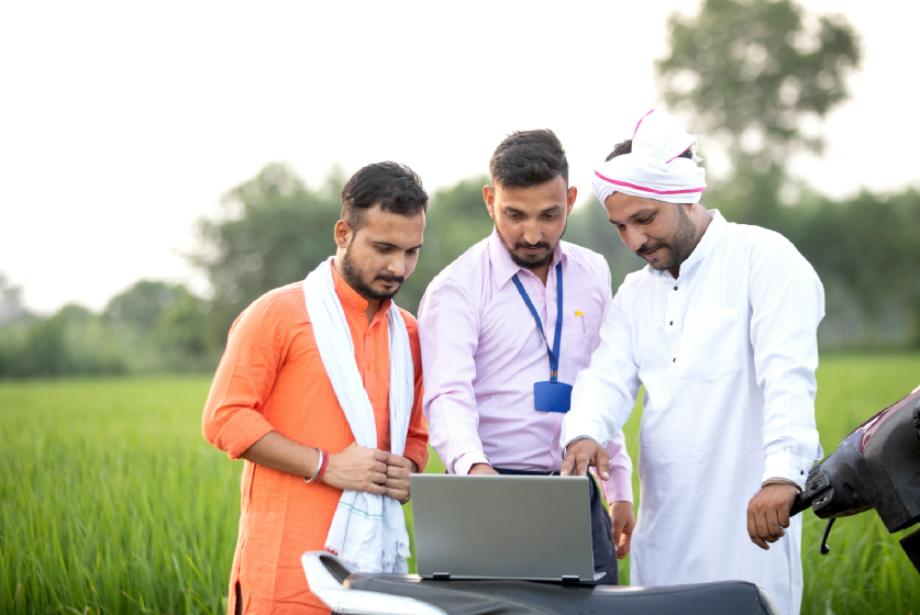 Sales man in an agri field showing farmers the concept in laptop